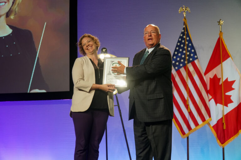 Dr. Haley Armstrong (left) accepting the Fraternity Advisor of the Year award from former Grand High Alpha Jeff Stuerman